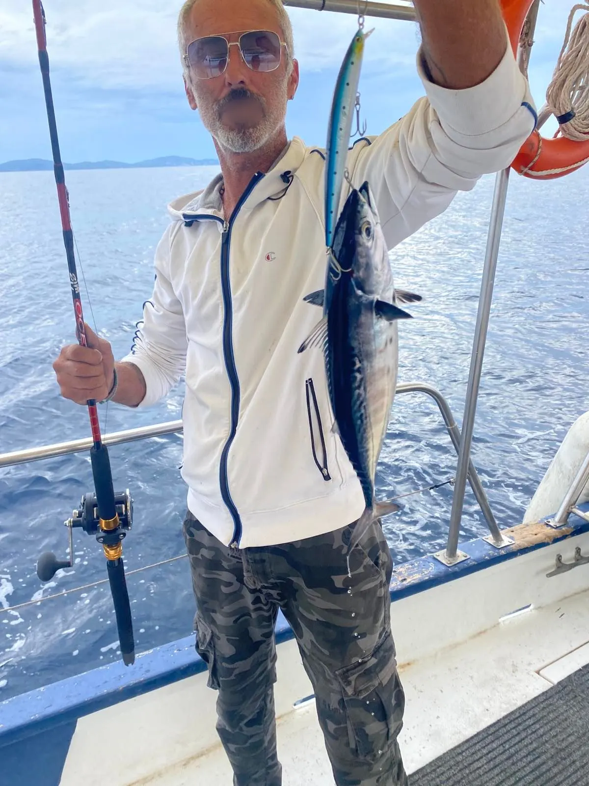 Dimitris holding a bonito caught on a lure, rod still in hand