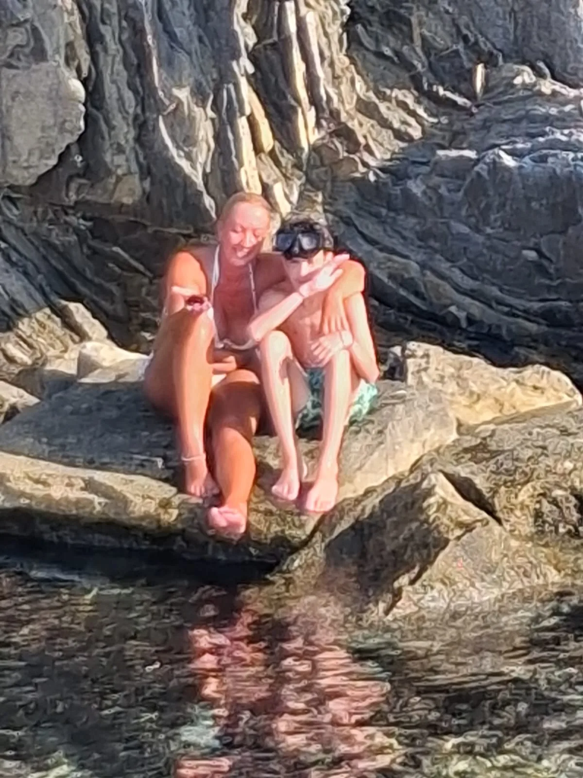 Victoria and her son resting on the rocks at a swimming stop