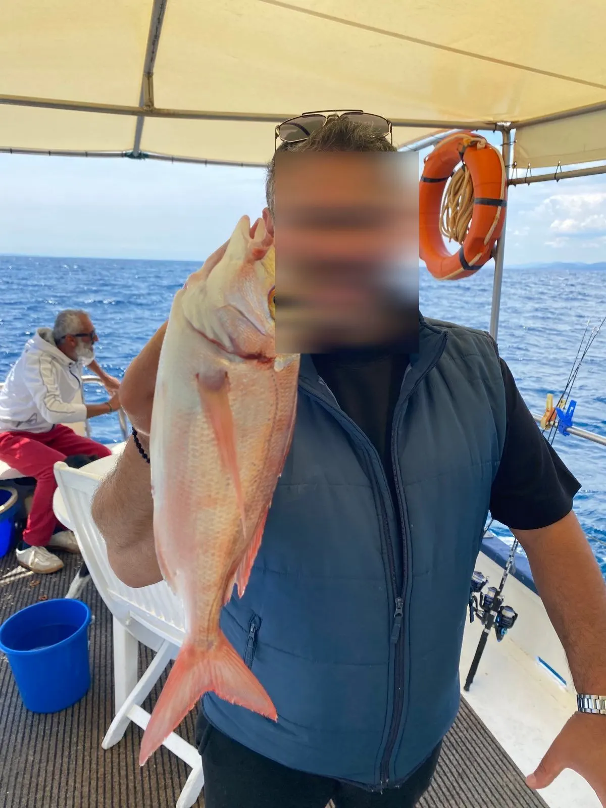 A guest holding a pandora aboard with the face privacy-protected, Dimitris behind him