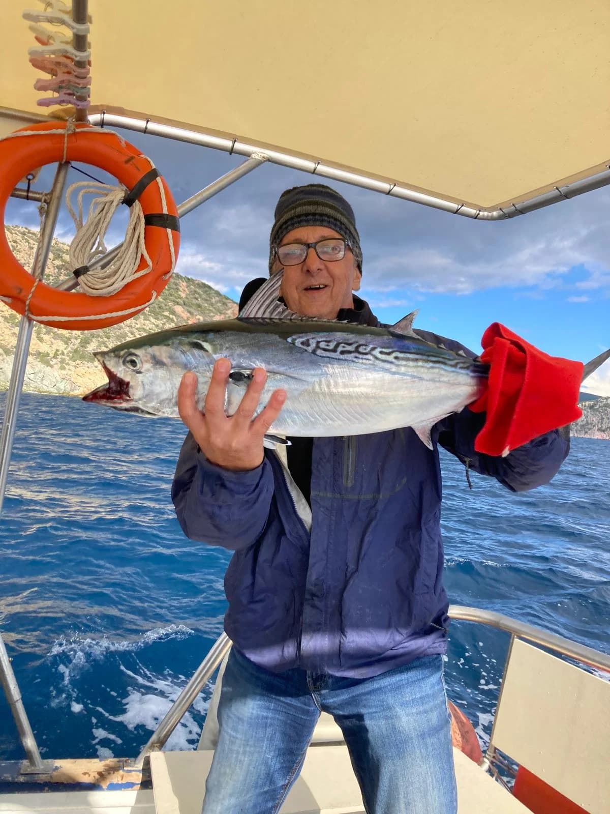 An adult guest holding a large fish aboard Fishing 4 You