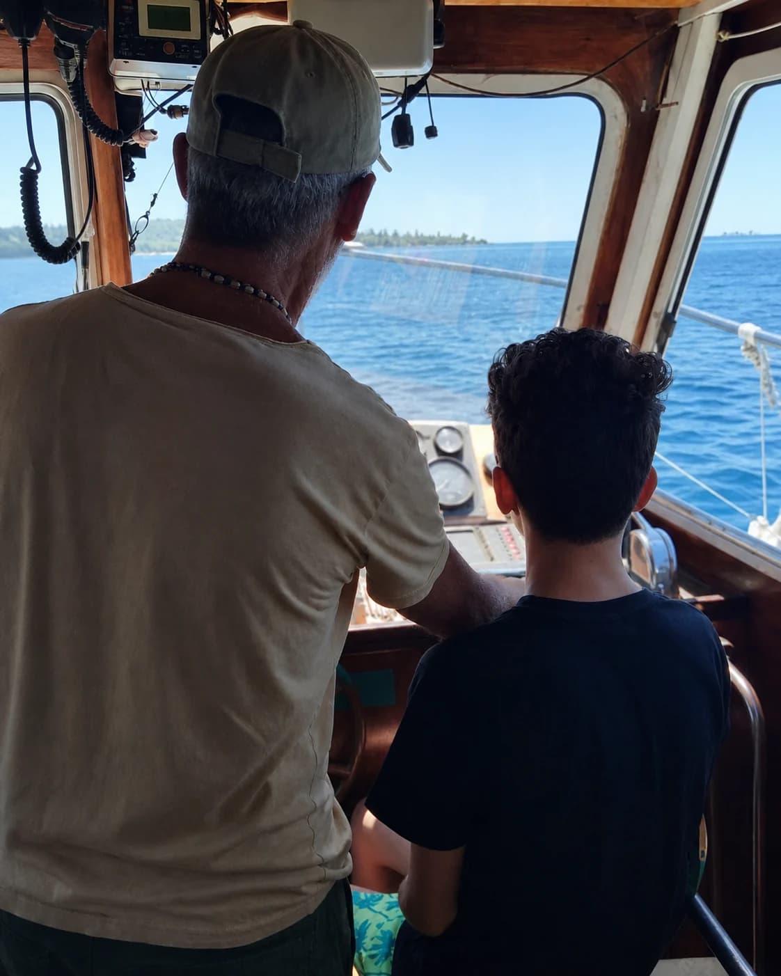 A guest learning at the boat helm, photographed from behind