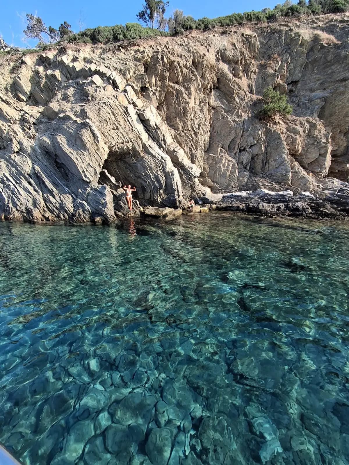Clear turquoise water over rocks beside the cliffs of Kelyfos